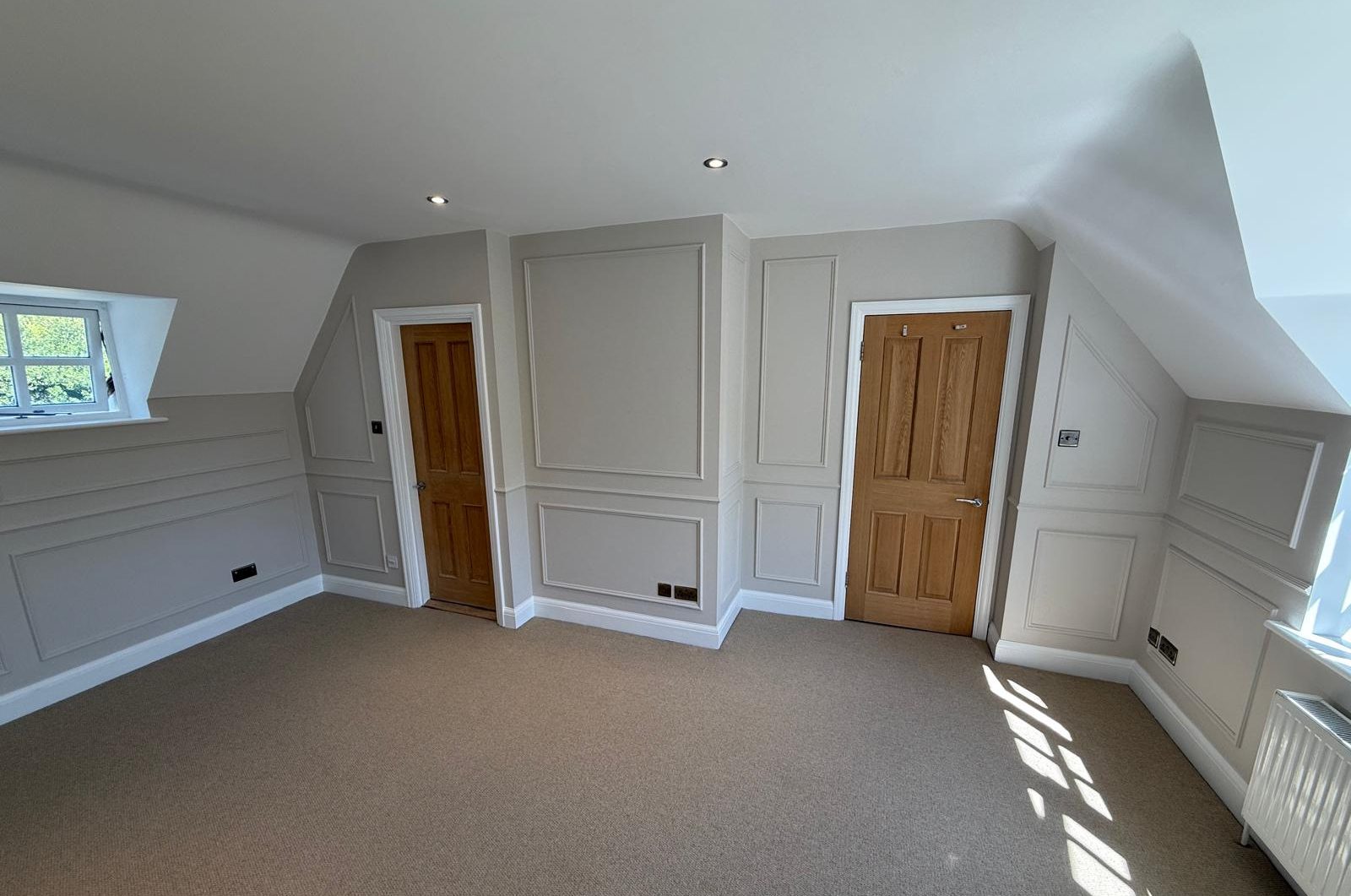 Fitted wall panelling and decoration around two oak doors in a loft bedroom, Esher